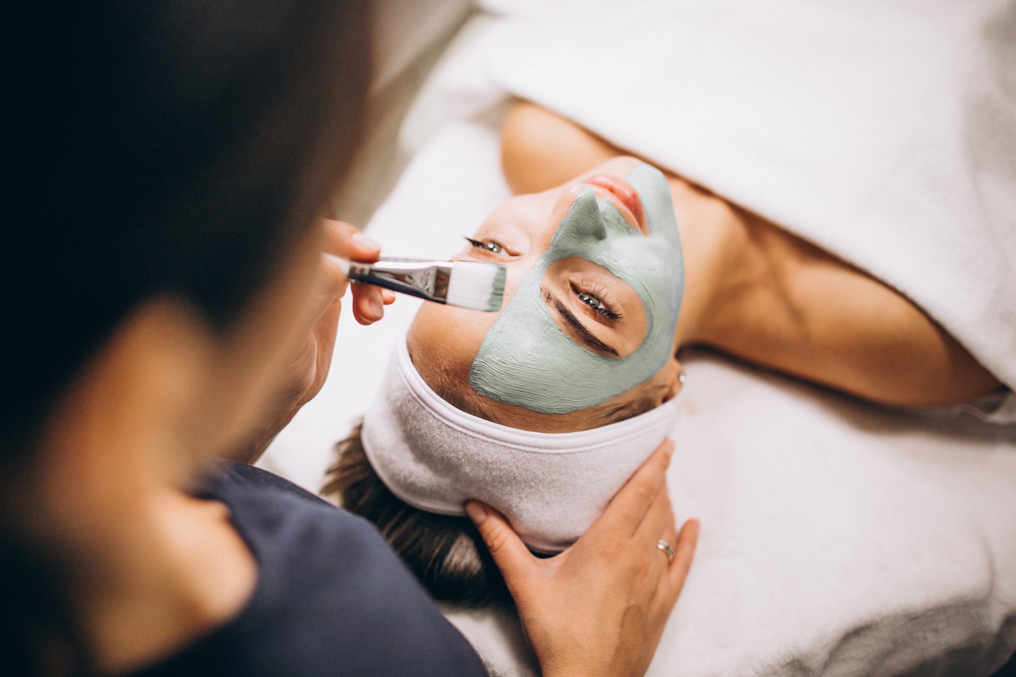 cosmetologist-applying-mask-face-client-beauty-salon